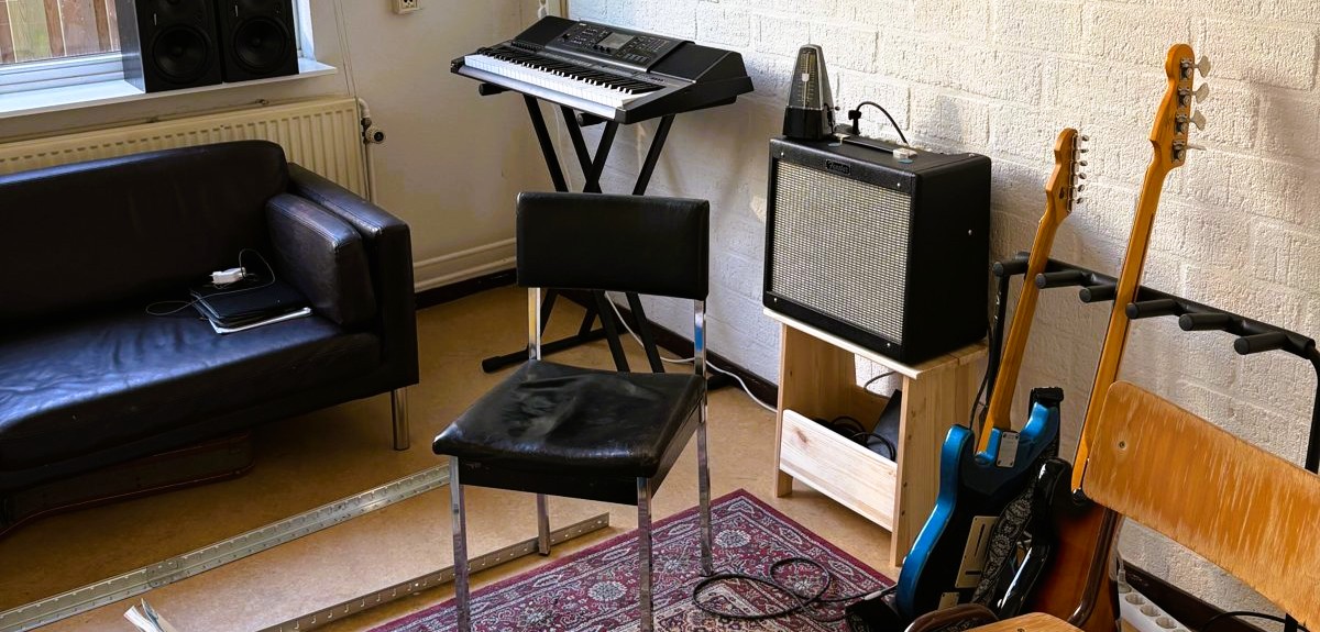 Lesruimte voor gitaarles in Utrecht met versterker, gitaren en bluesfoto's aan de muur